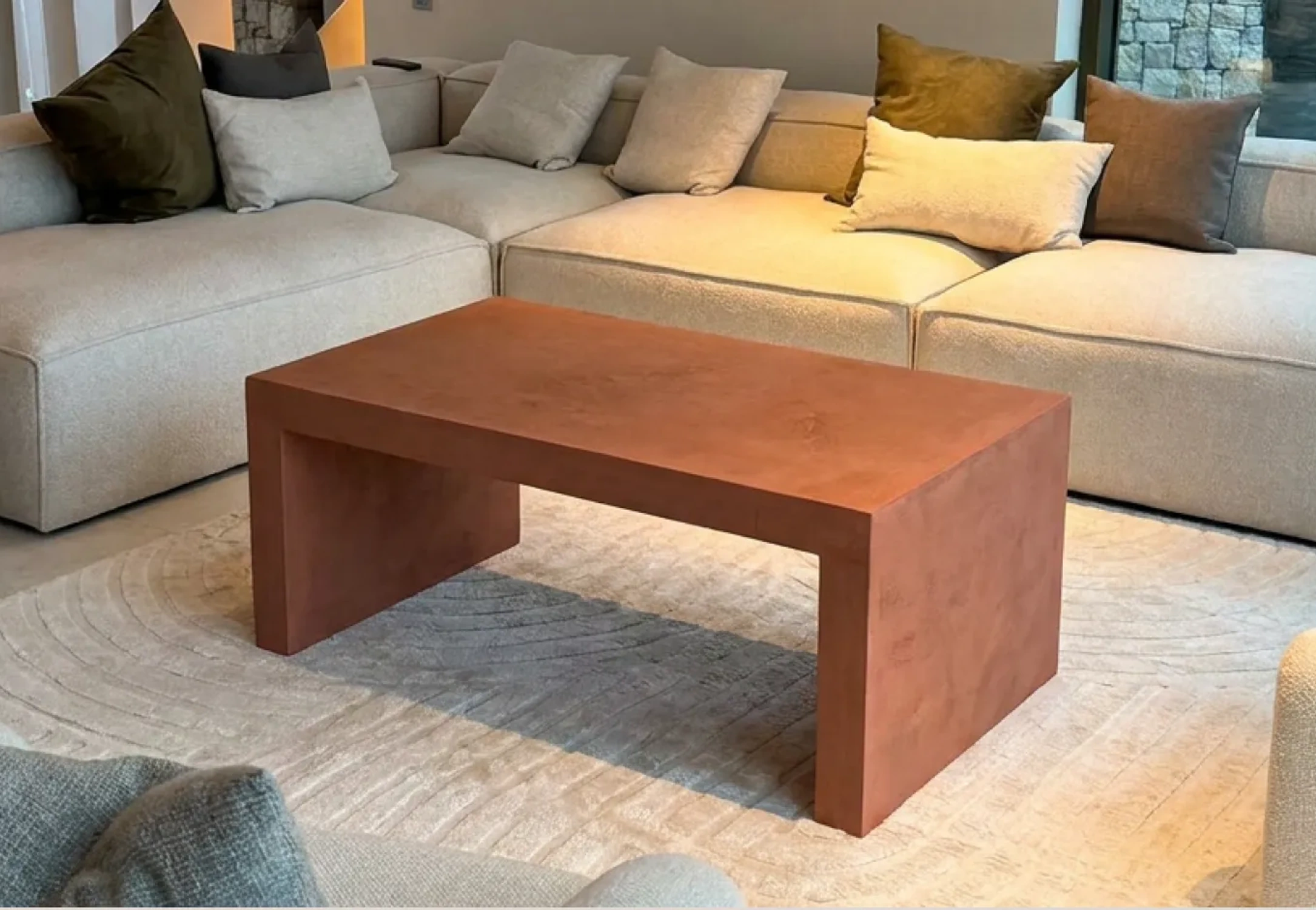 Handcrafted terracotta-toned microcement coffee table in a lived-in room